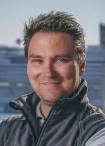 Ein Mann in einer Weste steht vor einem Kreuzfahrtschiff.